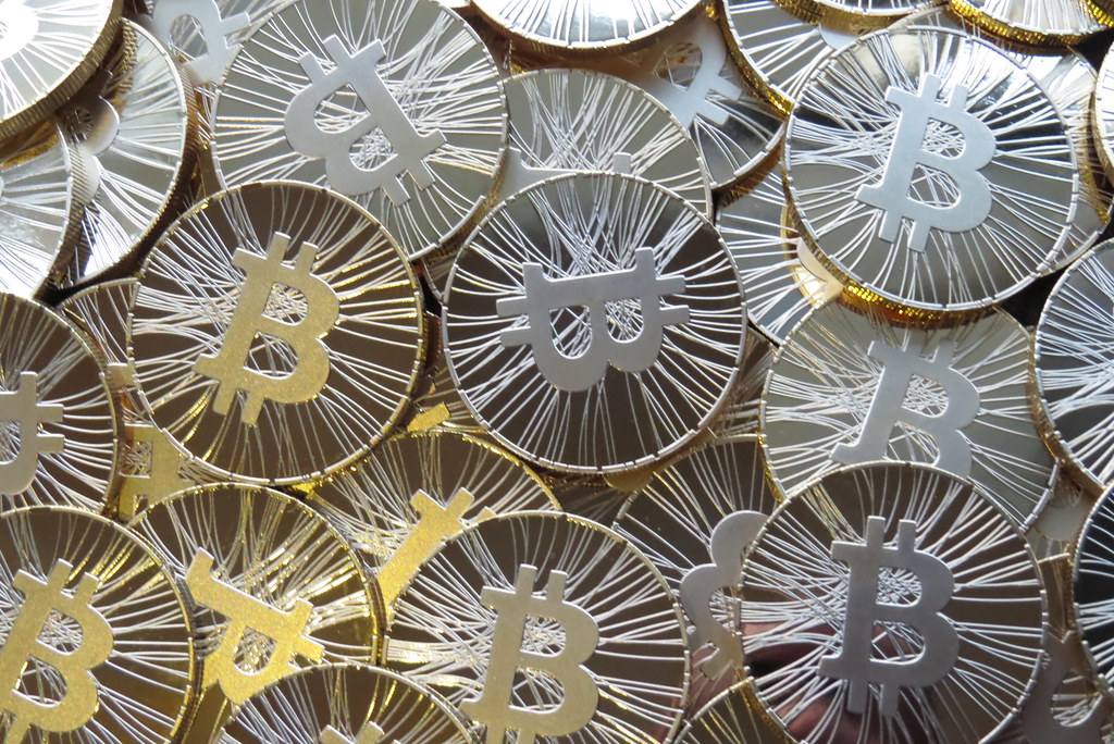 Piece physique de bitcoin doree posee sur une surface sombre, symbole de la cryptomonnaie
