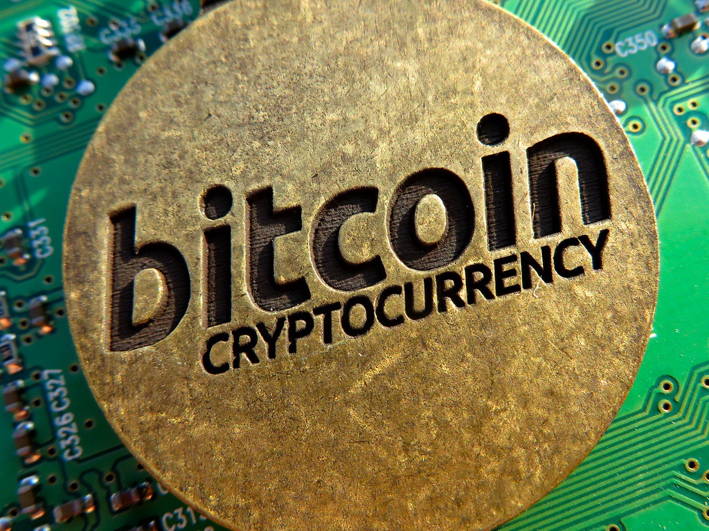 Pièces physiques de cryptomonnaie Bitcoin dorées posées sur une surface sombre